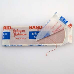 red string BAND-AID® Brand adhesive bandage