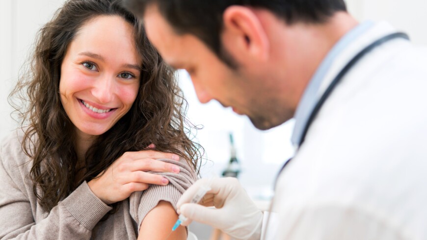 A photo of a doctor giving a flu vaccine to a smiling patient